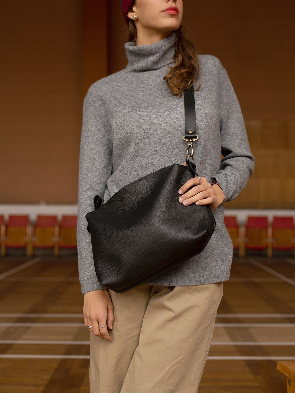7. Close-up of woman holding TOKS VISOKS ROBIN large black leather handbag, focusing on vegetable-dyed leather and craftsmanship