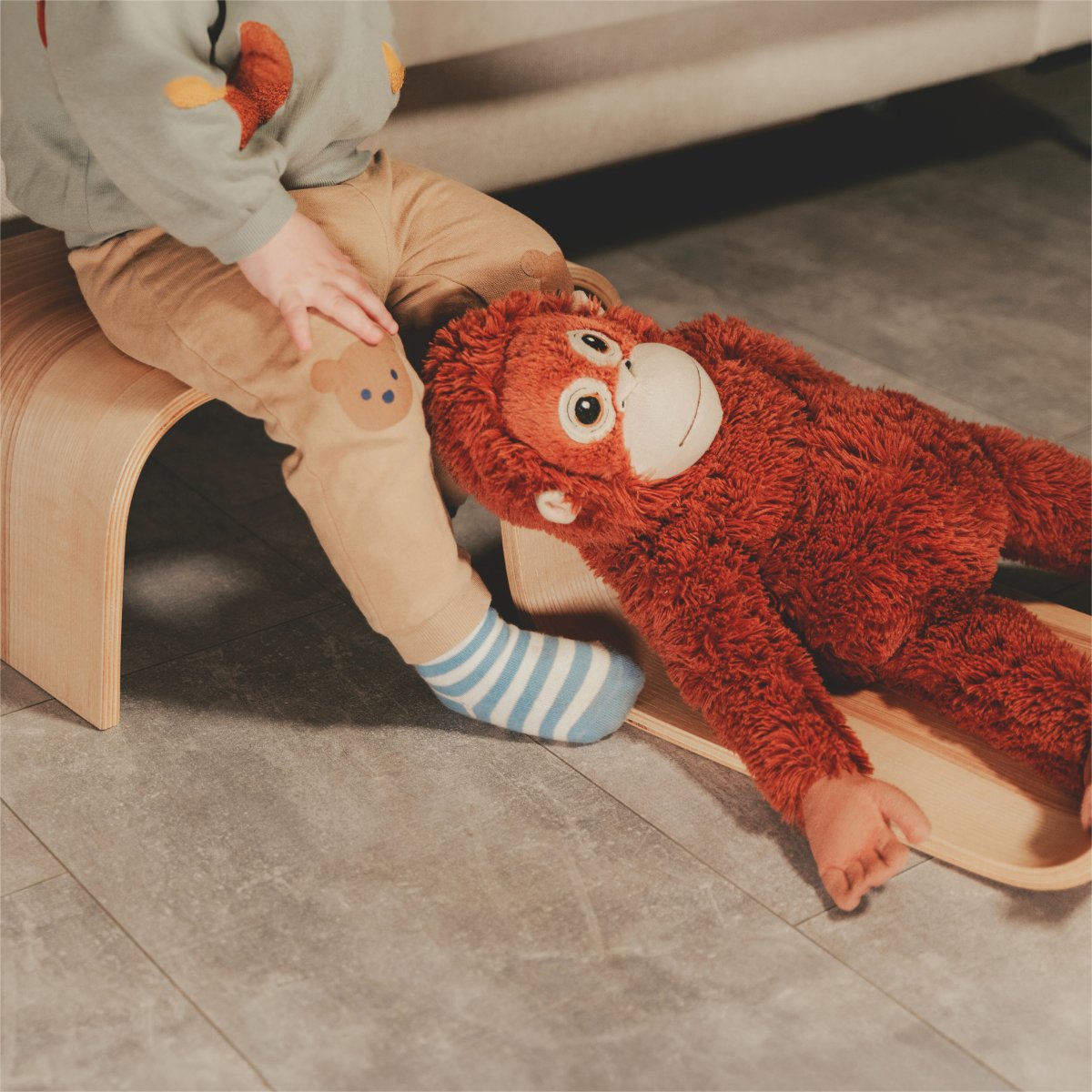 4. Child playing with plush toy on wooden step stool in a living room