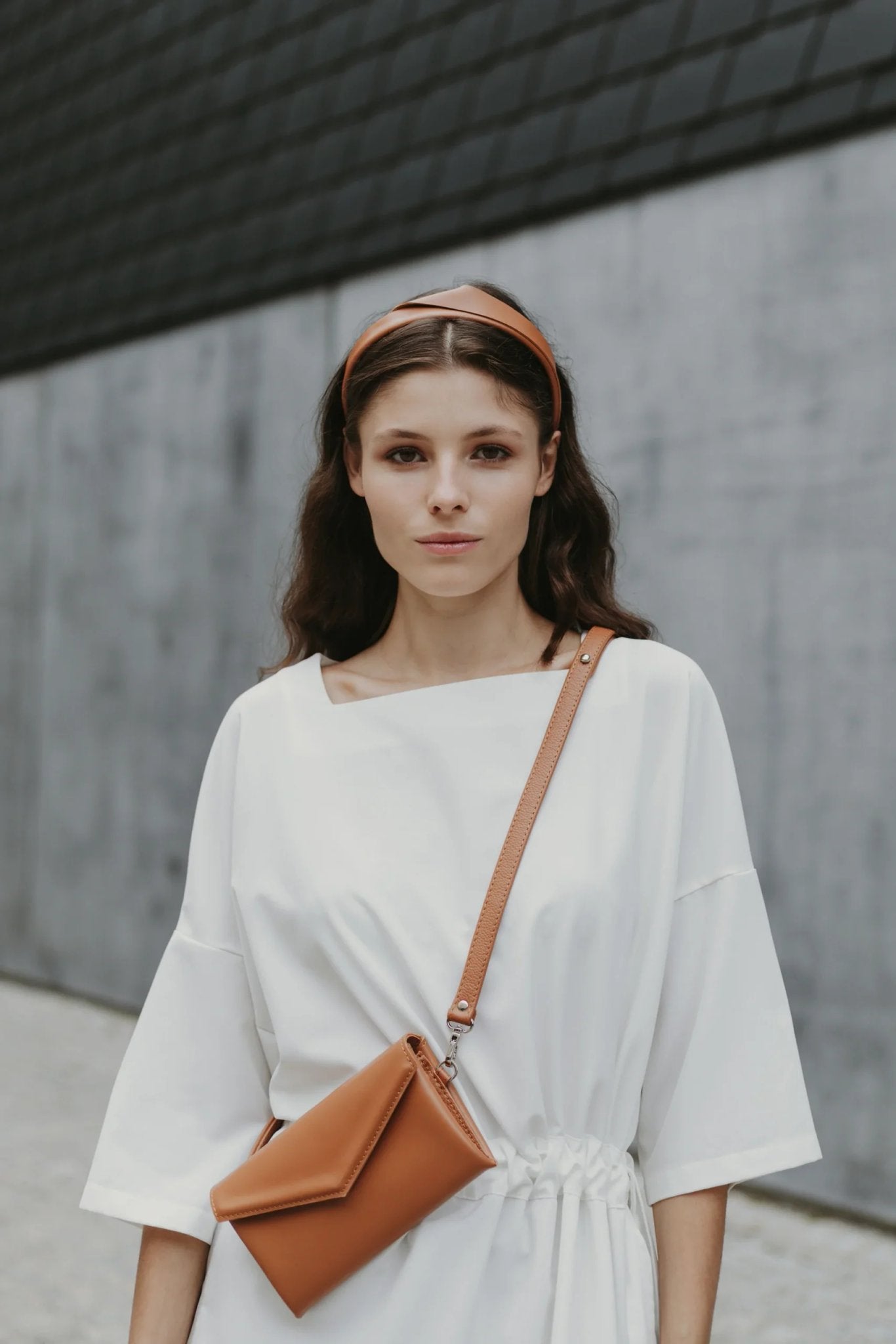 3. Women's brown Gerda Retter shoulder bag worn with white dress in urban setting