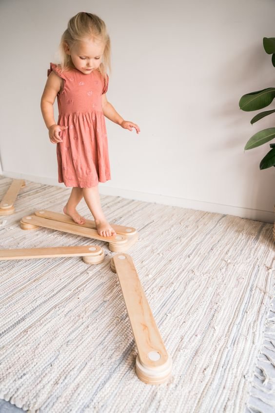 5. Child balancing on Ewart Woods wooden balance beams in a playroom