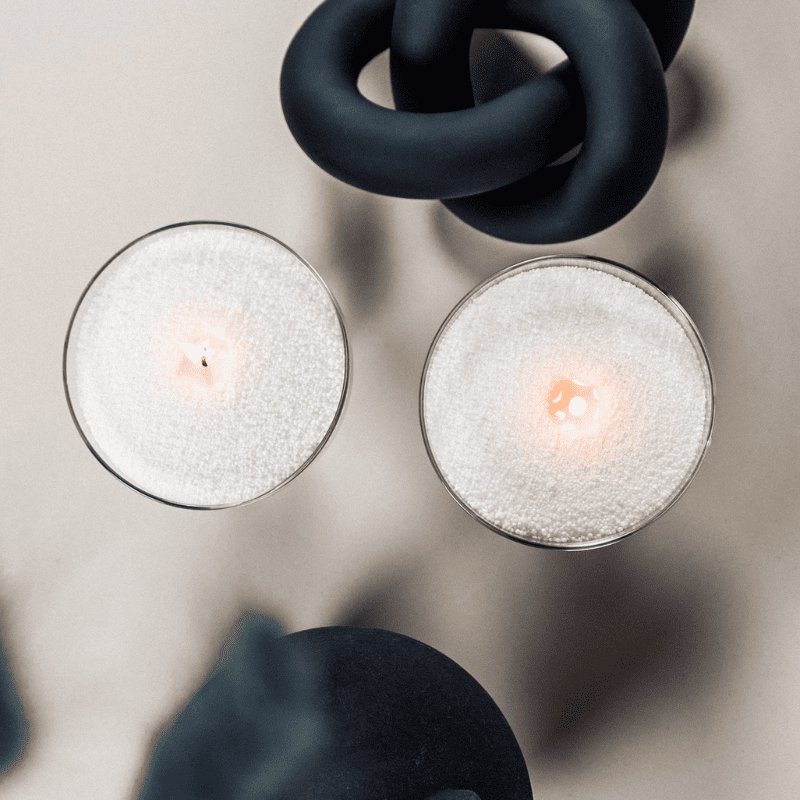 6. Overhead view of two lit Candledust powdered candles in glass containers with decorative elements