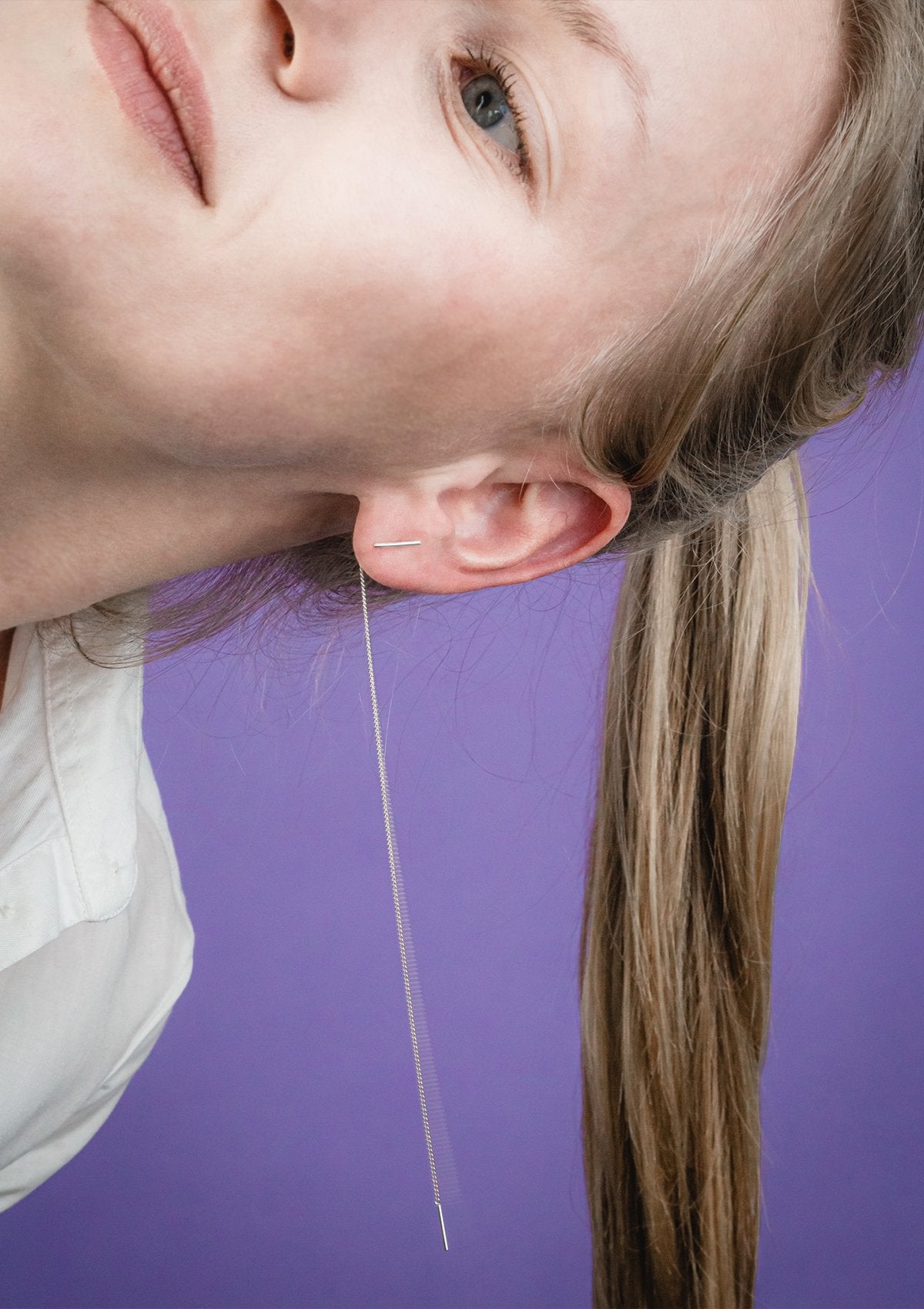 1. Woman wearing Maarja Palu SWING earrings with long silver chains and minimalist bar accents, shown in lifestyle setting