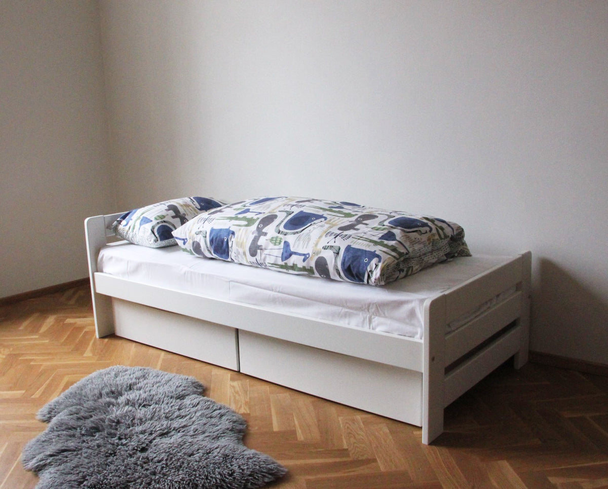 9. White children's bed with patterned bedding and grey rug on wooden floor