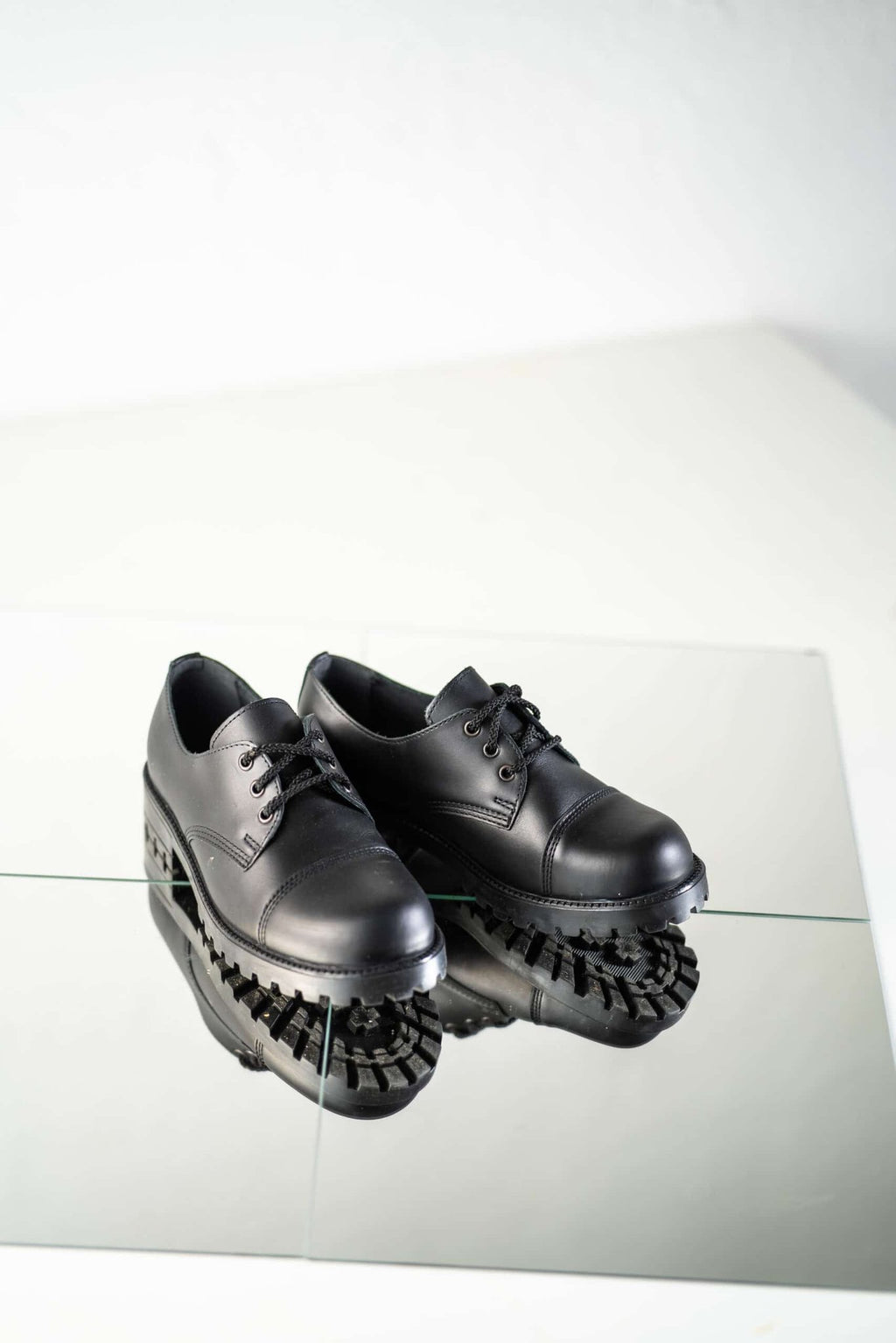 4. Studio shot of unisex black Samelin Widgets on reflective surface, showing front and side