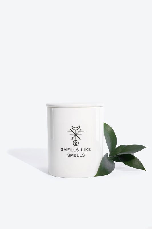 2. Smells Like Spells The Magician candle in white porcelain container with green leaf accent, studio shot