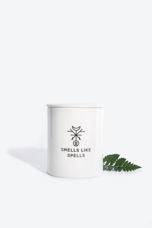 1. Smells Like Spells Scented Candle STRENGTH in white porcelain container with fern leaf, studio setting