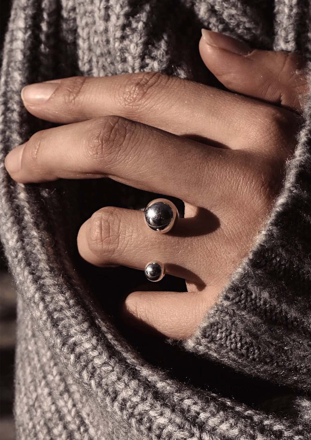 3. Close-up of NO MORE Big Bomb Multisize Ring in silver on hand, styled with a cozy gray sweater, emphasizing bold design