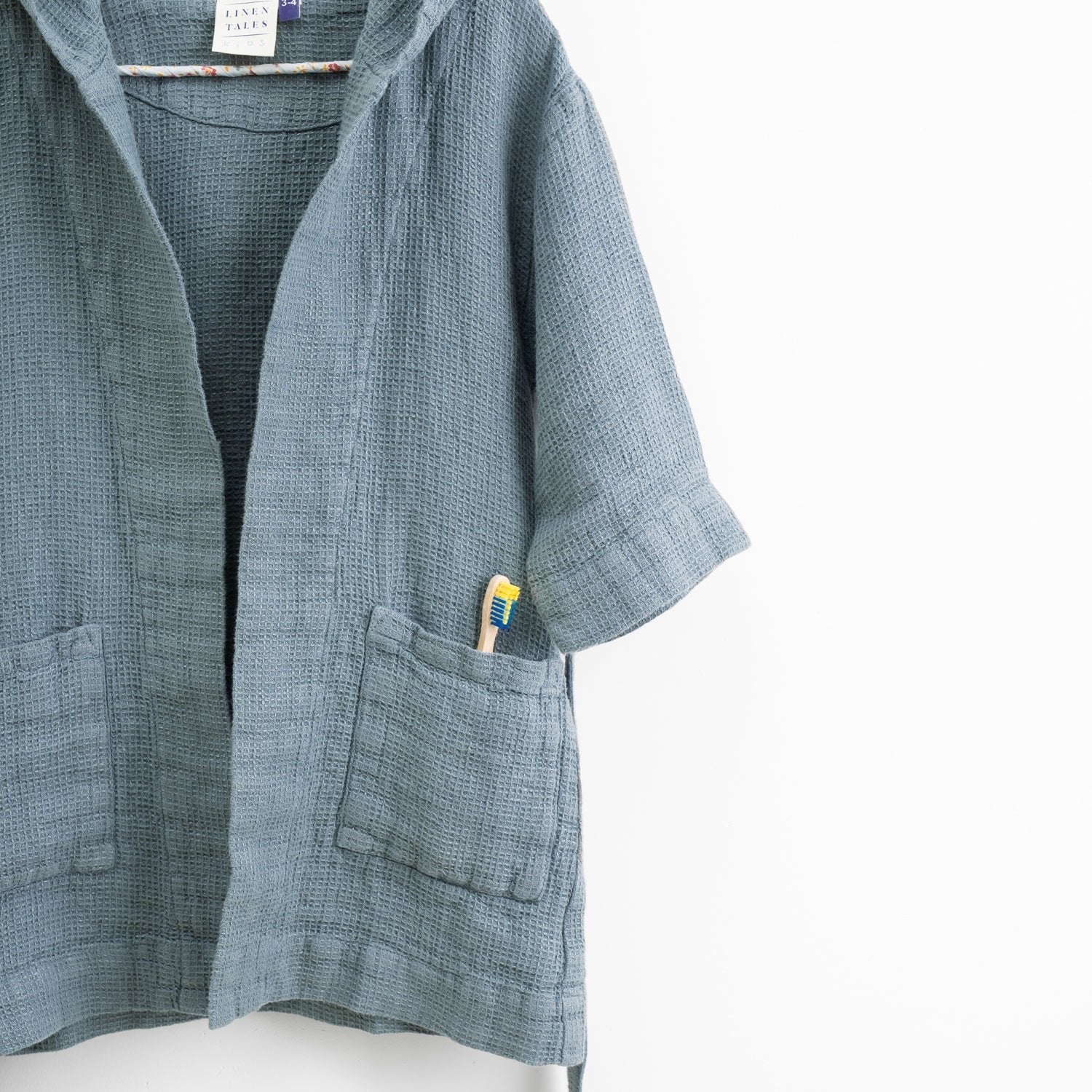 5. Close-up of kids' blue fog linen bathrobe showing pocket and hood detail