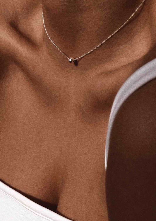 1. Woman wearing NO MORE Bubble Necklace in gold, styled with a white top, showcasing elegant design