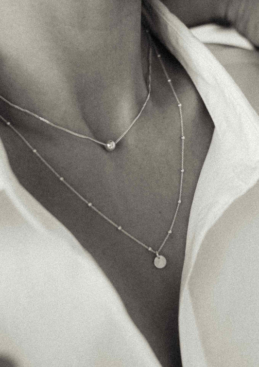 2. Close-up of woman layering NO MORE Bubble Necklace in gold with another necklace, highlighting versatility