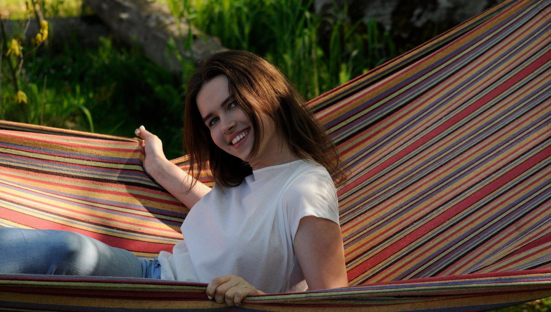 2. Woman relaxing in a hammock wearing Smarttan Tan-Through T-Shirt in coral, highlighting comfort and outdoor use