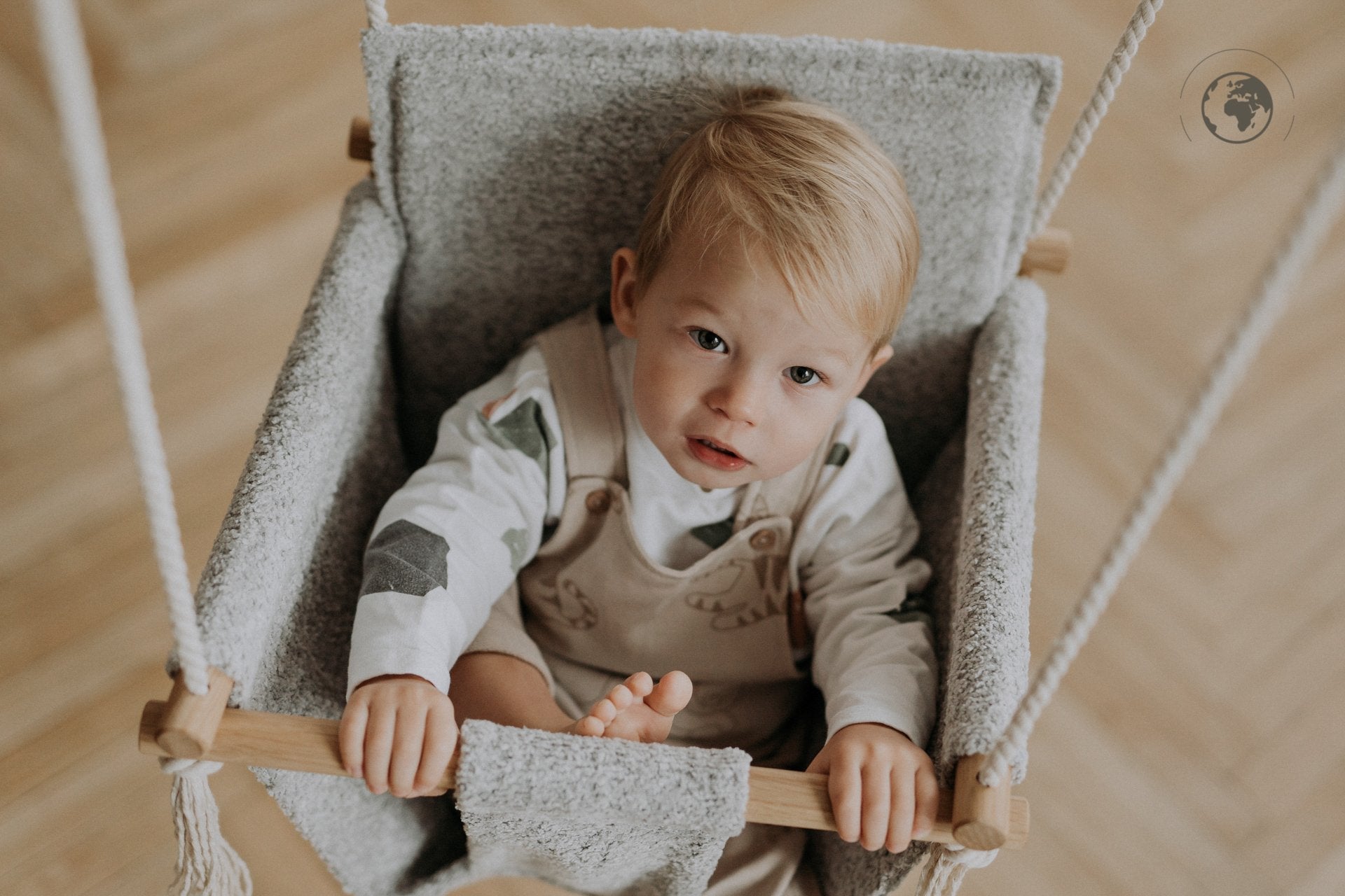2. Toddler sitting in bouclé stone grey swing with oak wood poles indoors