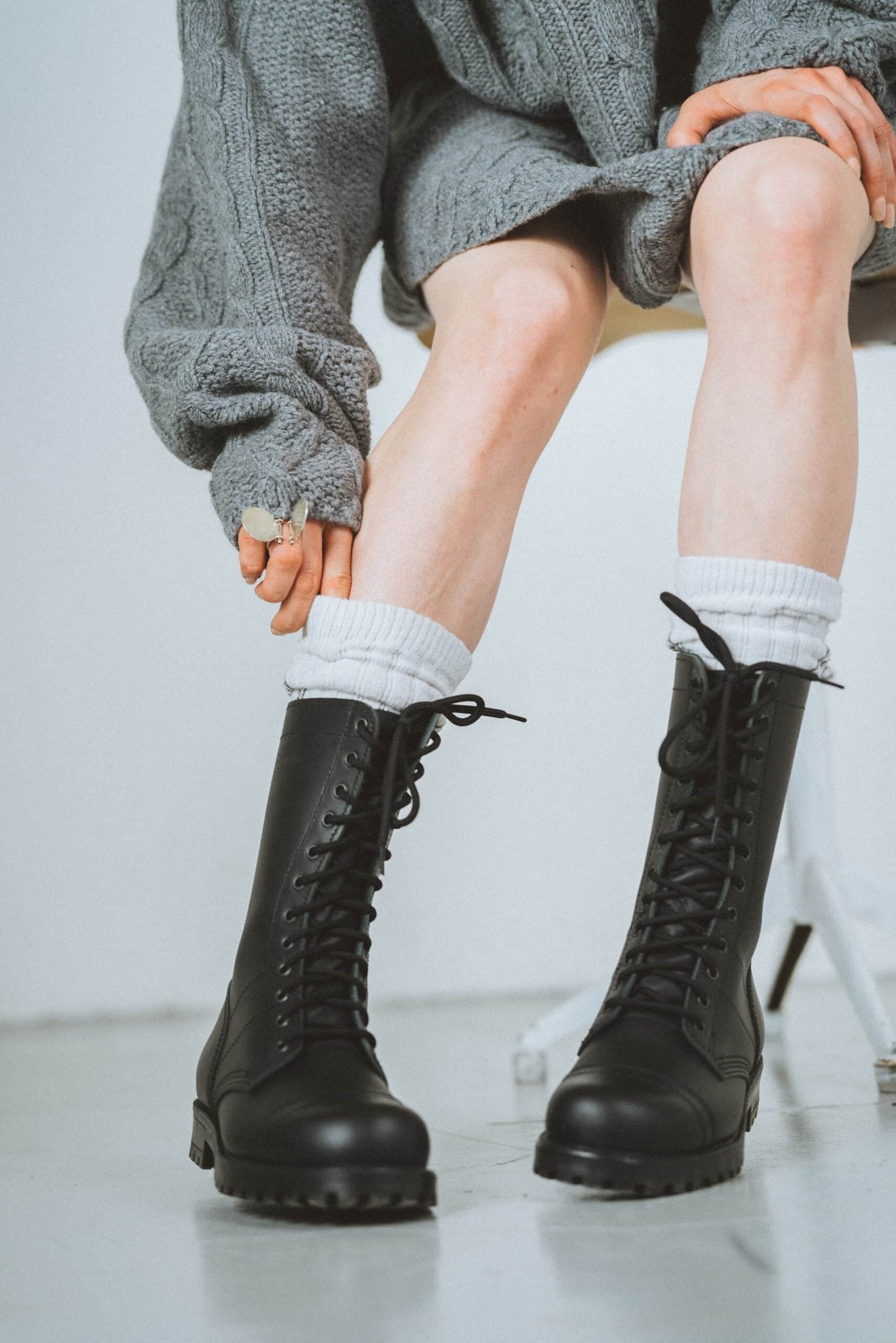 2. Woman adjusting socks while wearing Samelin 516 High Aviator Boots in black, showcasing urban style