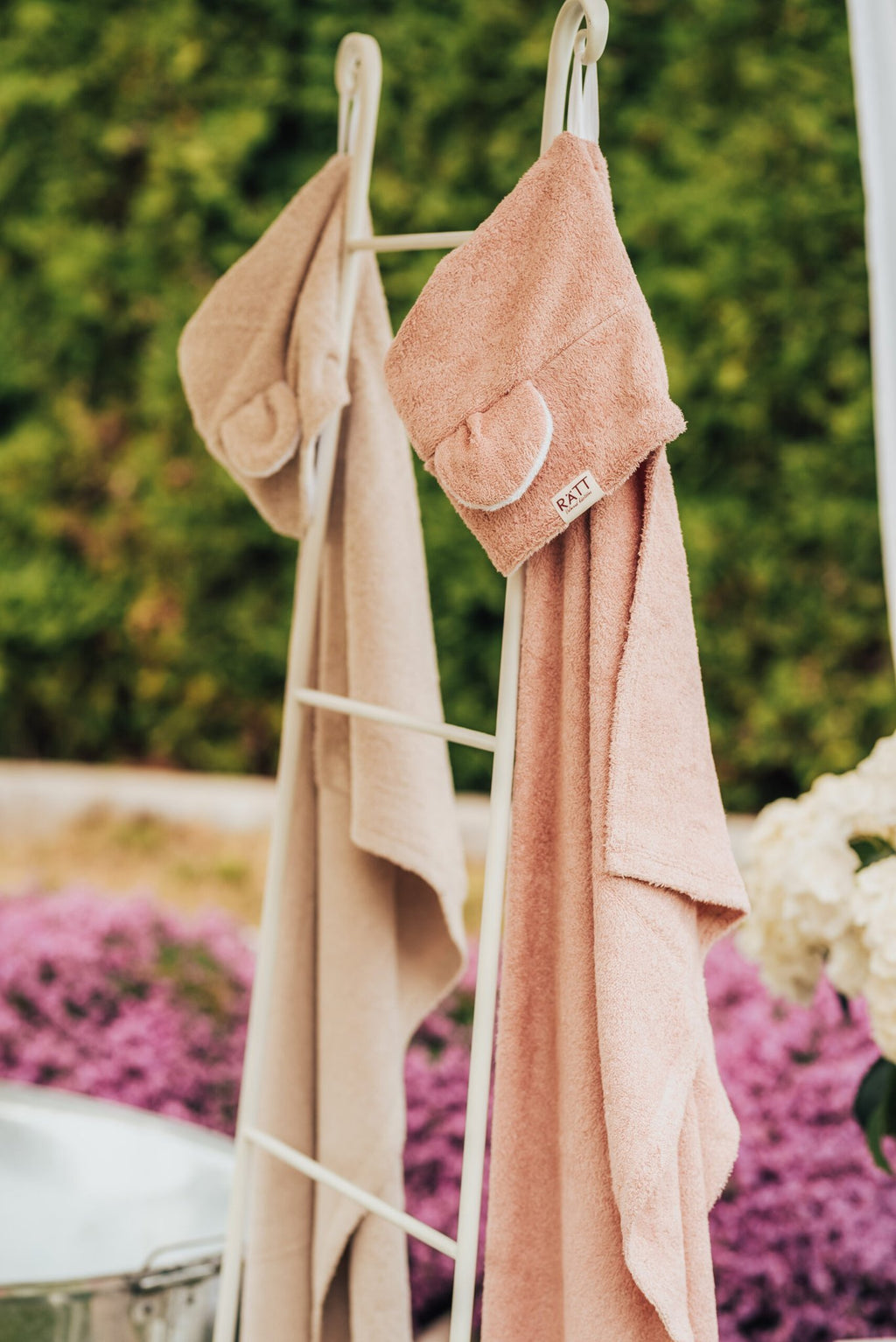 8. RÄTT hooded baby bath towels in beige and pink hanging on rack, garden setting