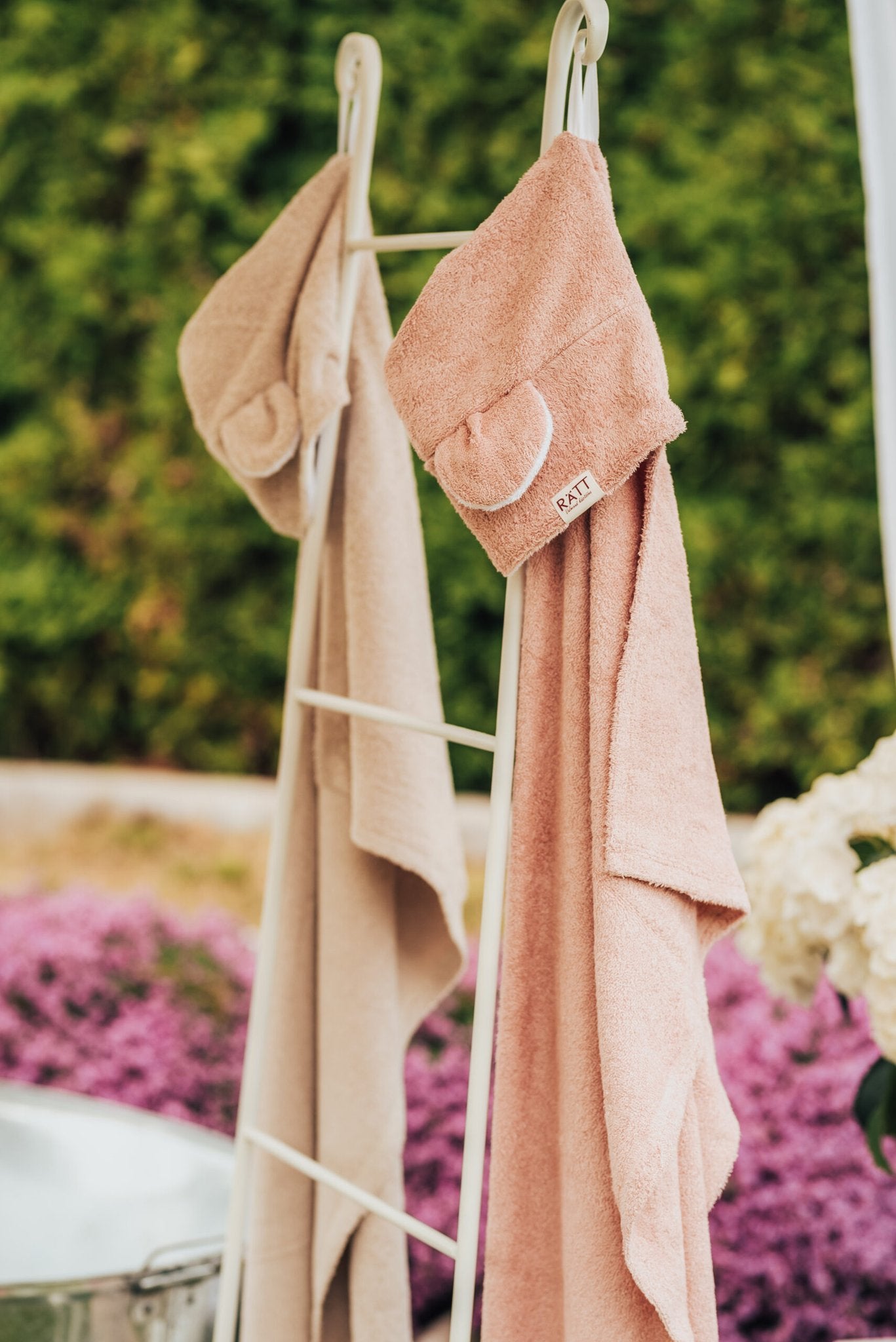 8. RÄTT hooded baby bath towels in beige and pink hanging on rack, garden setting