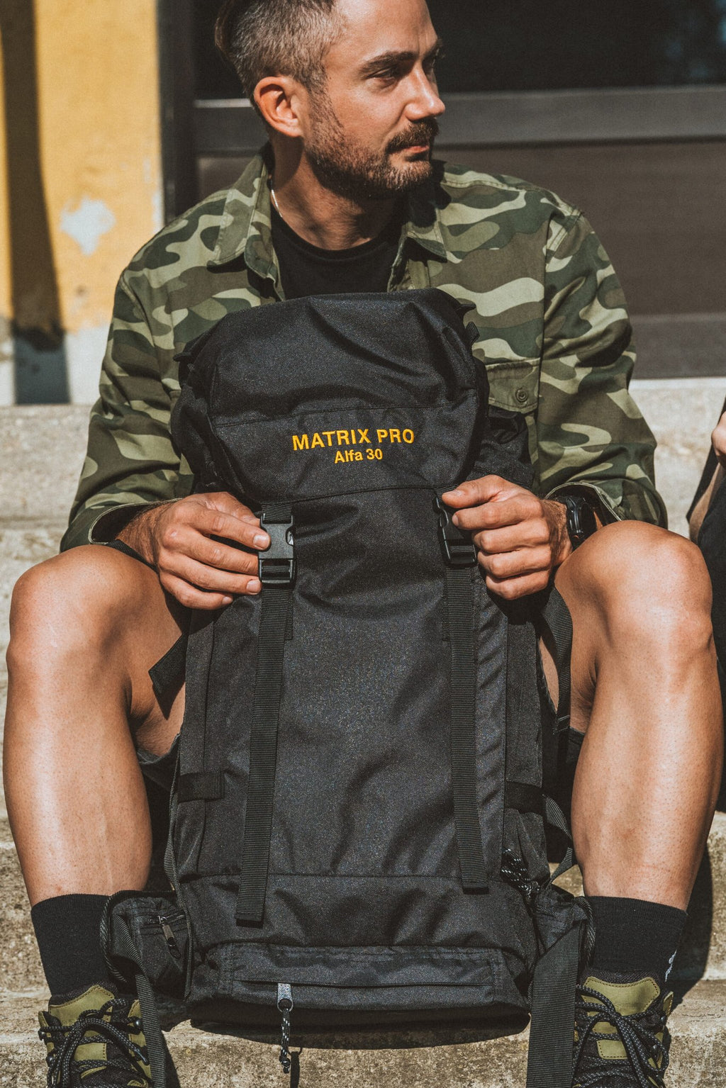 1. Man sitting with Matrix Pro Alfa 30 hiking bag in outdoor setting
