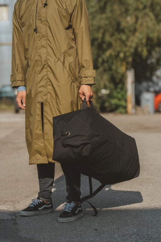 2. Close-up of Galvi Linda waterproof rain jacket in olive green, highlighting Velcro-fastened sleeves and large black storage bag