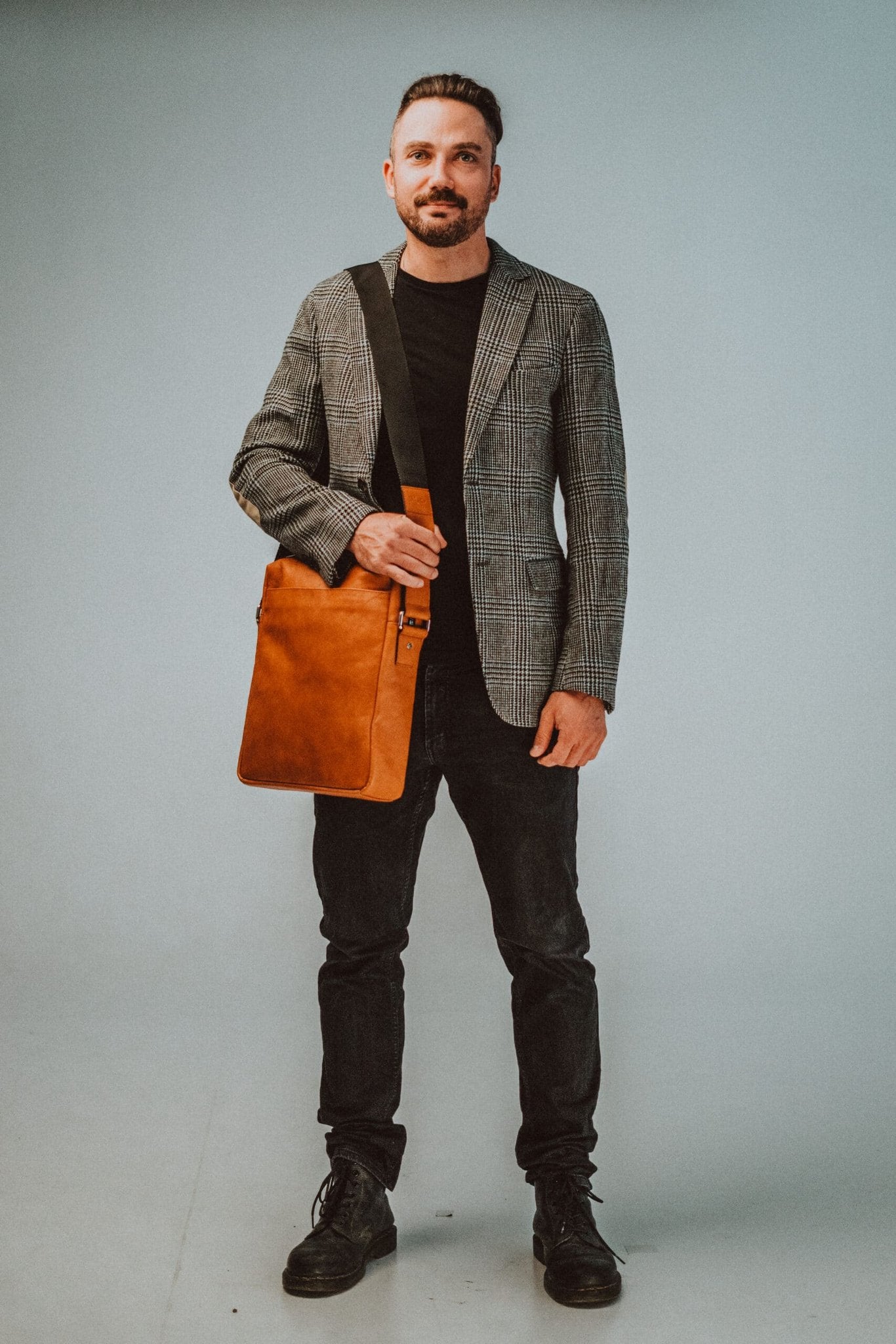 1. Men's large shoulder bag No. 38 by Papillon in natural leather, worn crossbody with a plaid blazer and black jeans