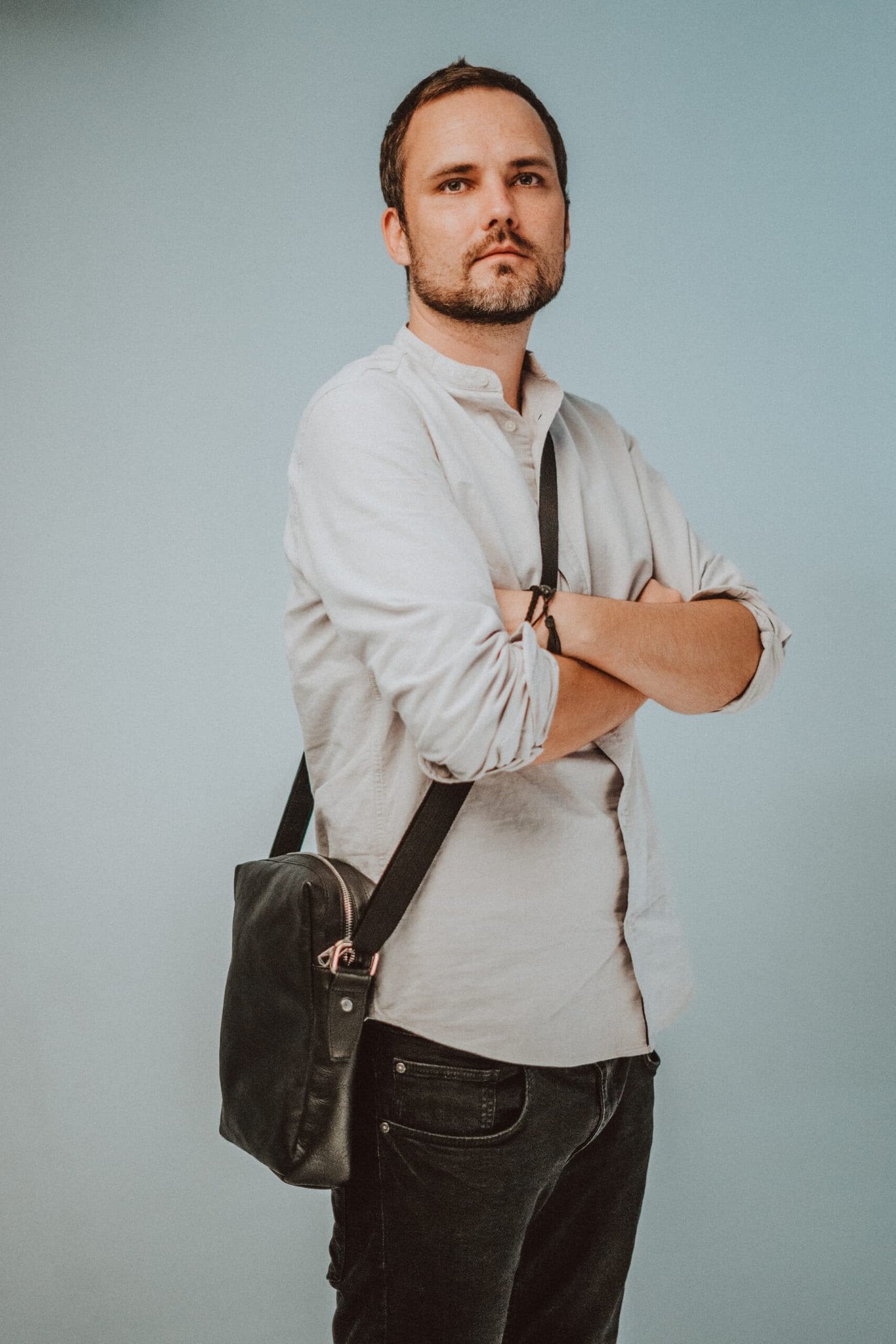 1. Men's black leather Papillon Small Shoulder Bag No. 37 worn crossbody, showcasing adjustable strap and sleek design
