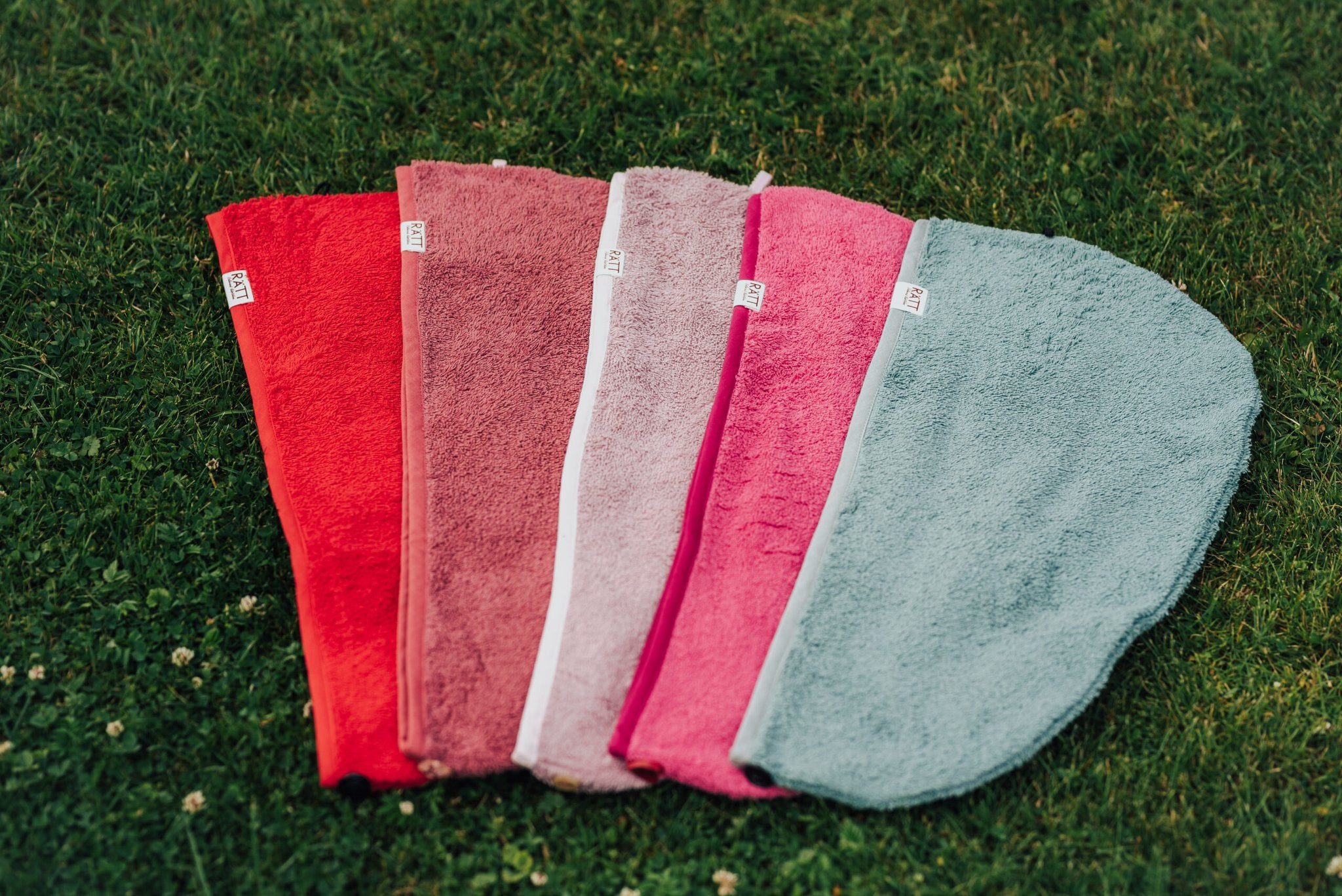 4. Flat lay of RÄTT bamboo terry hair wraps in various colors on grass, showcasing eco-friendly design