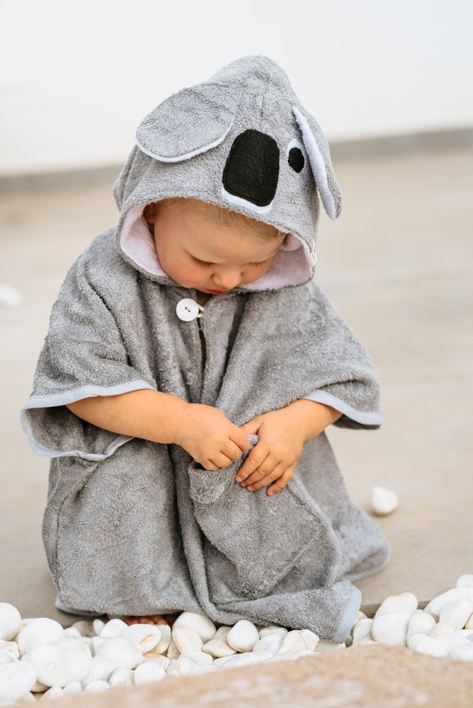 4. Close-up of child in gray RÄTT Short-Sleeve Poncho KOALA sitting on stones