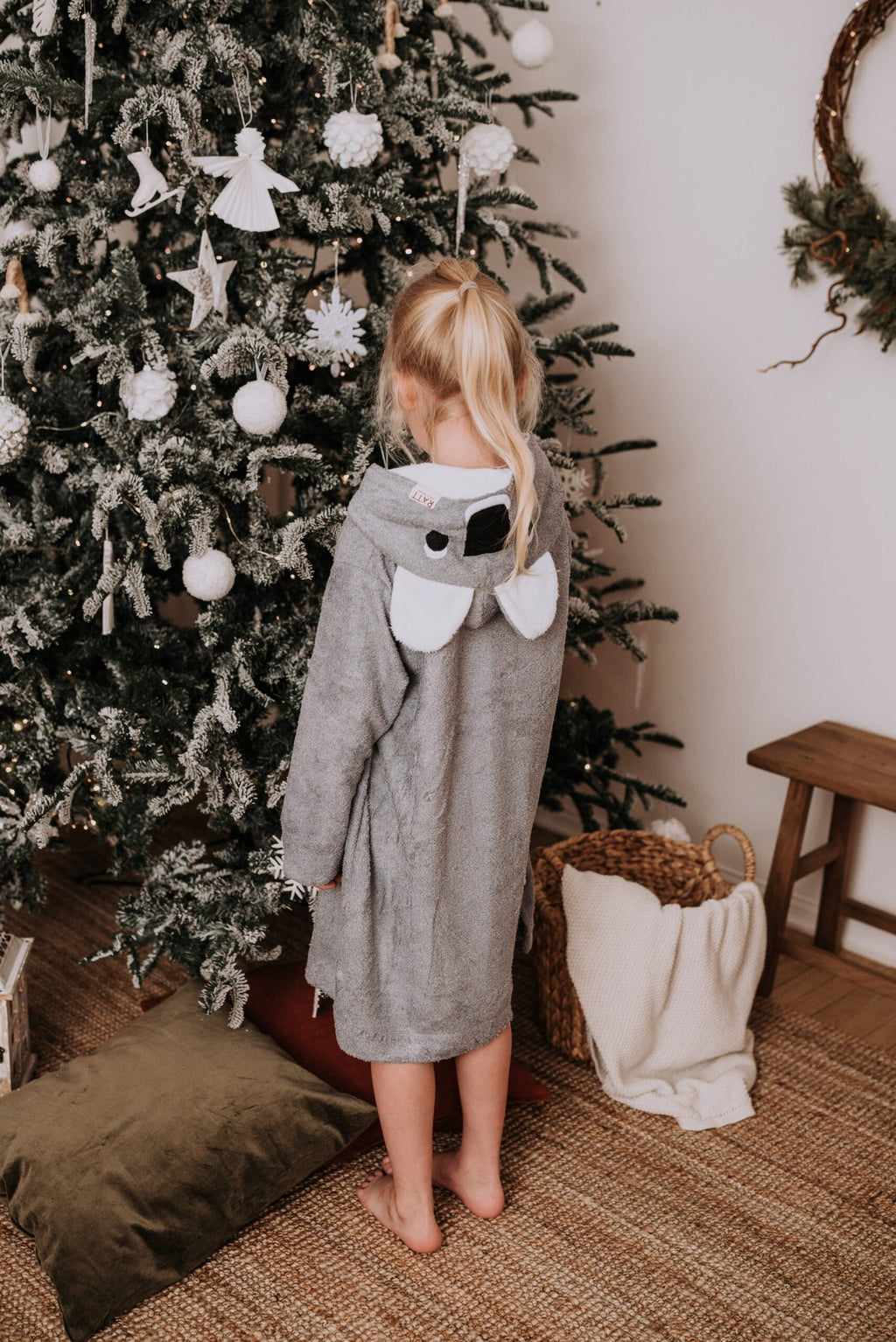 4. Back view of toddler in grey RÄTT long-sleeve poncho KOALA, standing by a Christmas tree