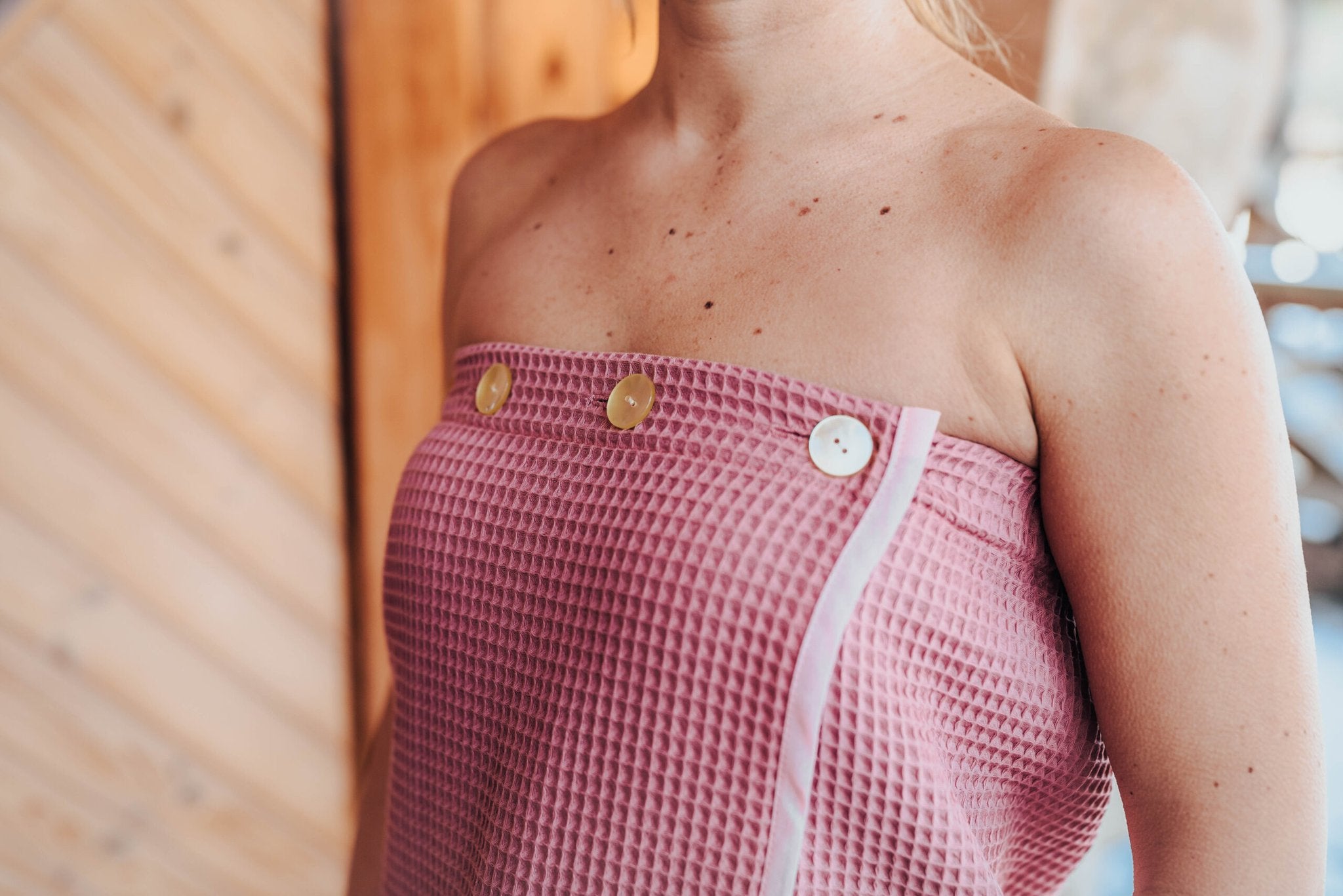 7. Close-up of pink RÄTT spa wrap button closure, highlighting adjustable fit