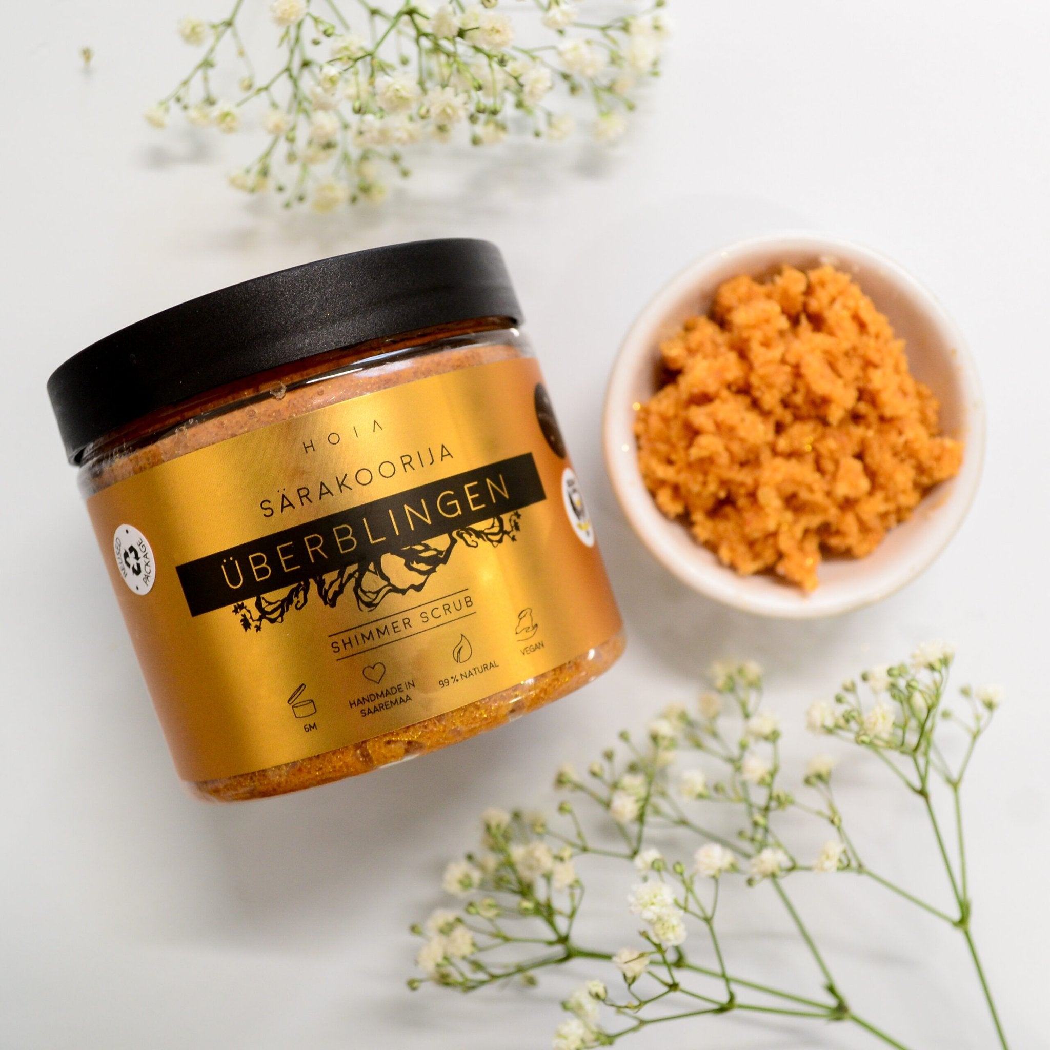 2. HOIA homespa Shimmering Body Scrub Überblingen jar with scrub in bowl, surrounded by flowers