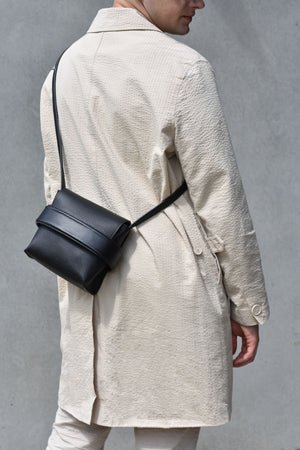 2. Unisex black Luce shoulder bag by Gerda Retter Design worn crossbody with long strap, shown from back in lifestyle setting