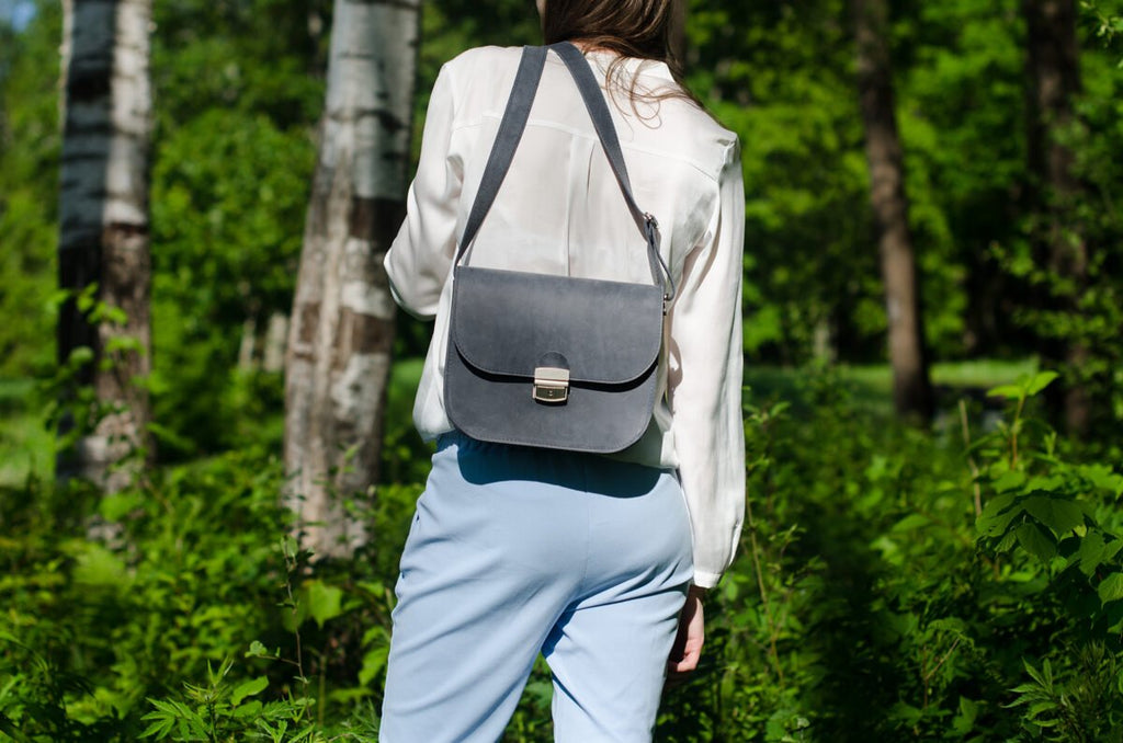 8. Zelma Kraft grey leather saddle bags hanging on tree branch, showcasing natural leather texture