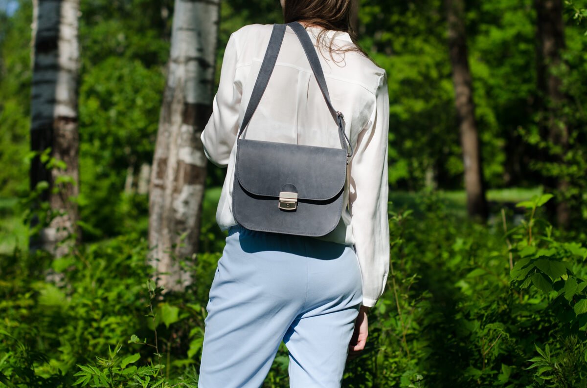 8. Zelma Kraft grey leather saddle bags hanging on tree branch, showcasing natural leather texture