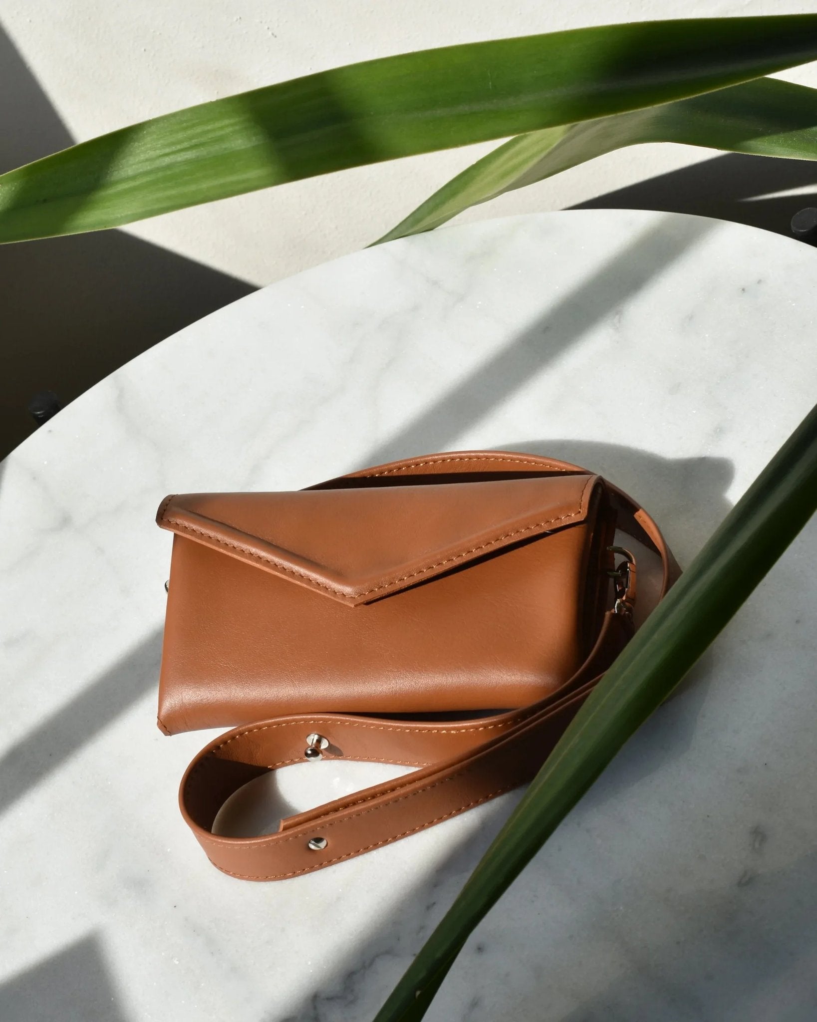 9. Brown leather waist and shoulder bag by Gerda Retter Design, shown closed on marble surface