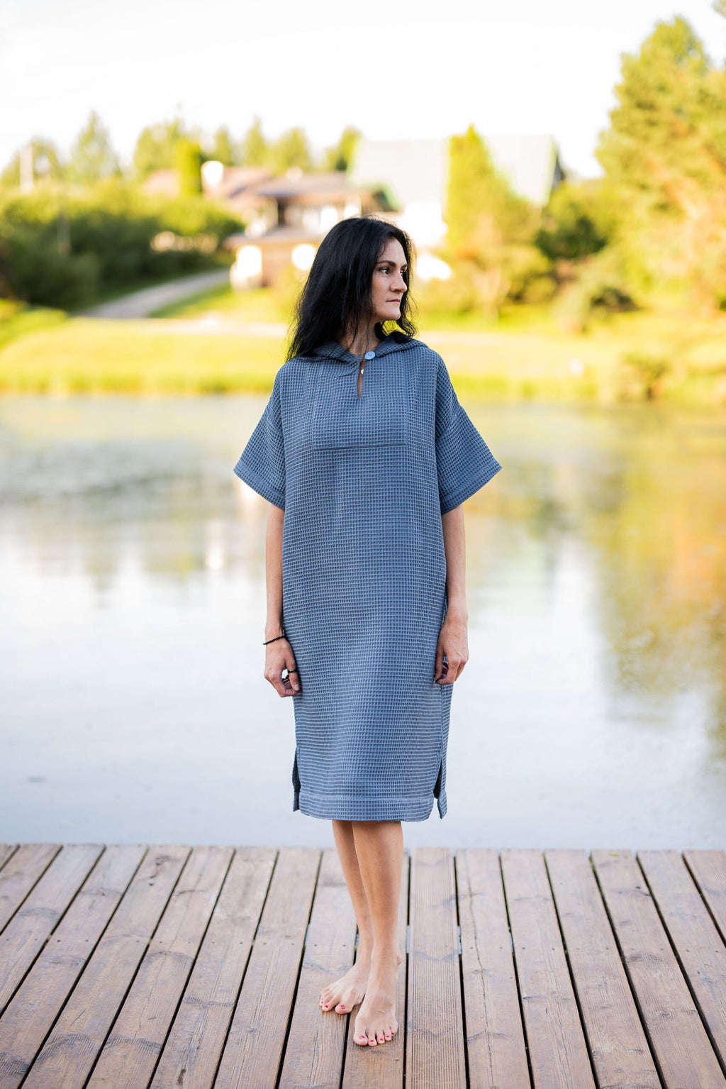 15. Woman standing on dock in blue RÄTT short-sleeve surf poncho with hood