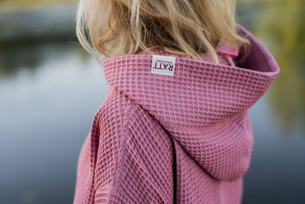 12. Close-up of pink RÄTT short-sleeve surf poncho hood with brand label