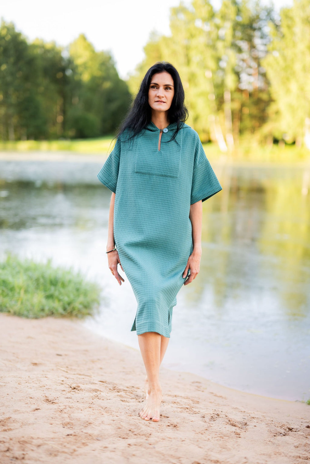 11. Woman walking on beach in teal RÄTT short-sleeve surf poncho with hood