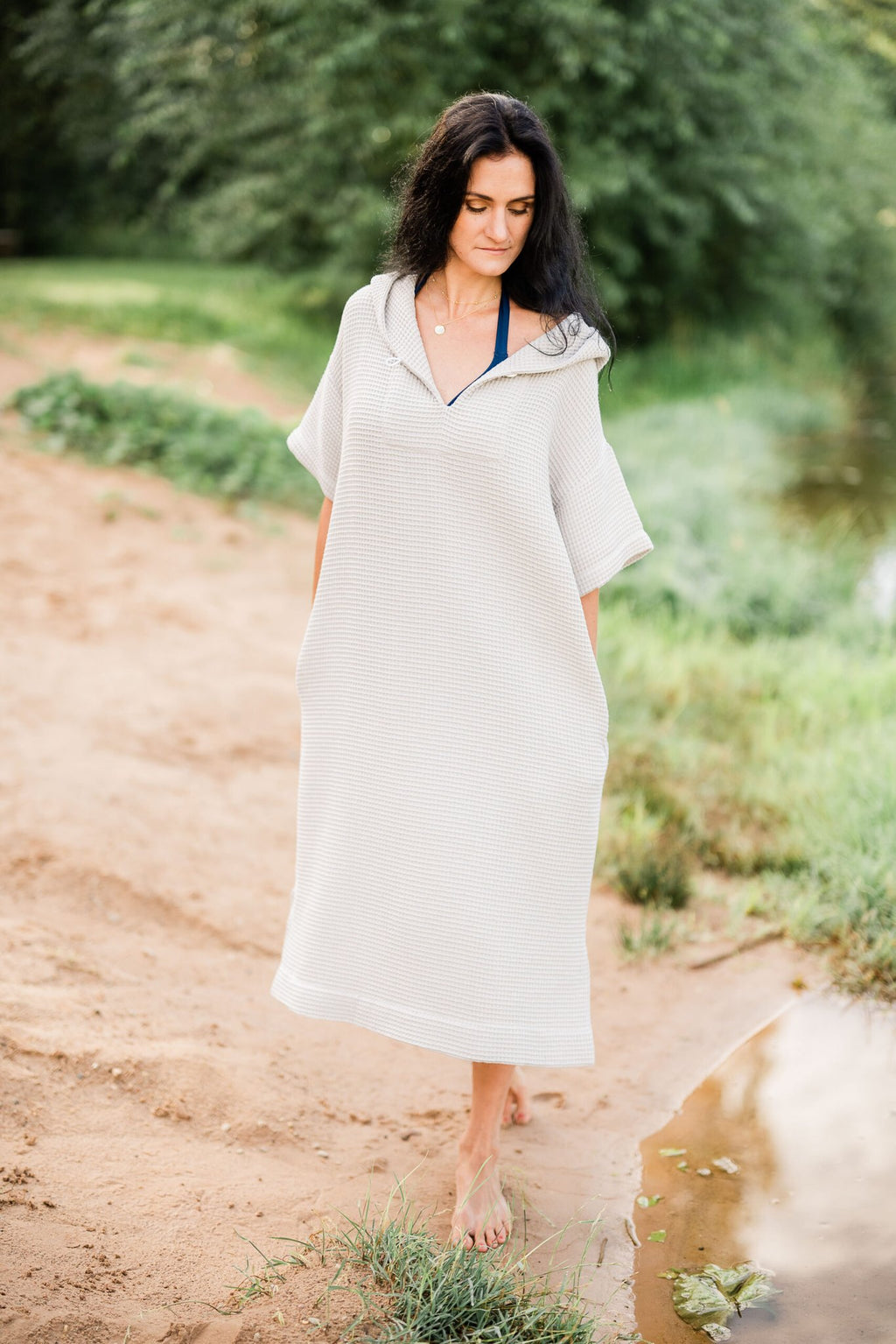6. Woman walking on beach in light grey RÄTT short-sleeve surf poncho with hood