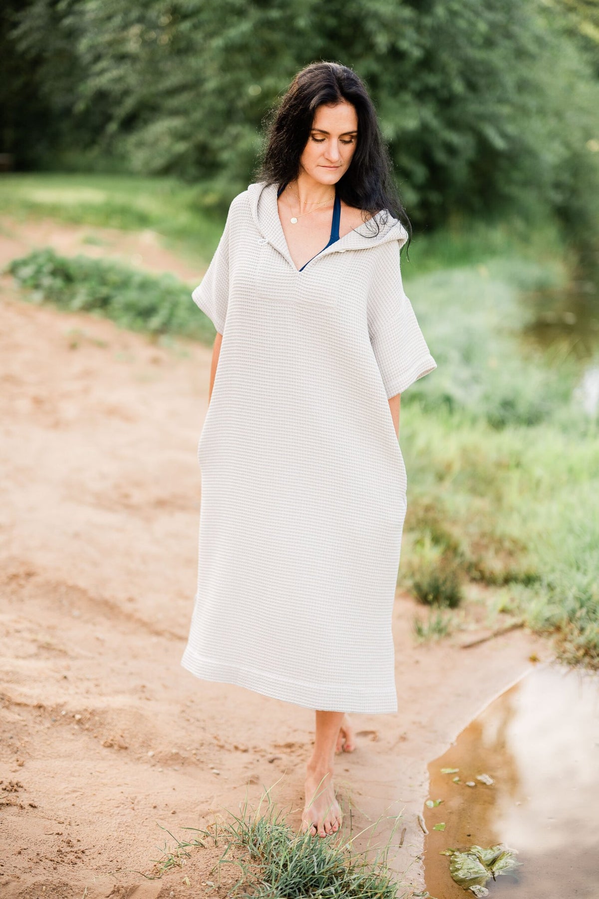 6. Woman walking on beach in light grey RÄTT short-sleeve surf poncho with hood
