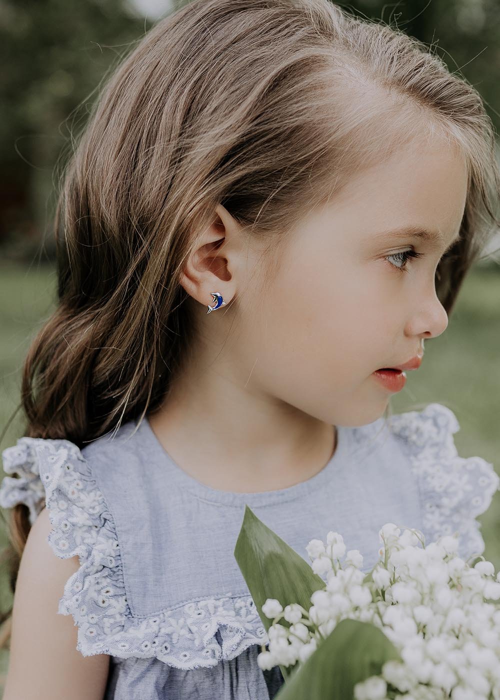 1. Girl wearing Dondella dolphin earrings in lifestyle setting, showcasing vibrant blue enamel design