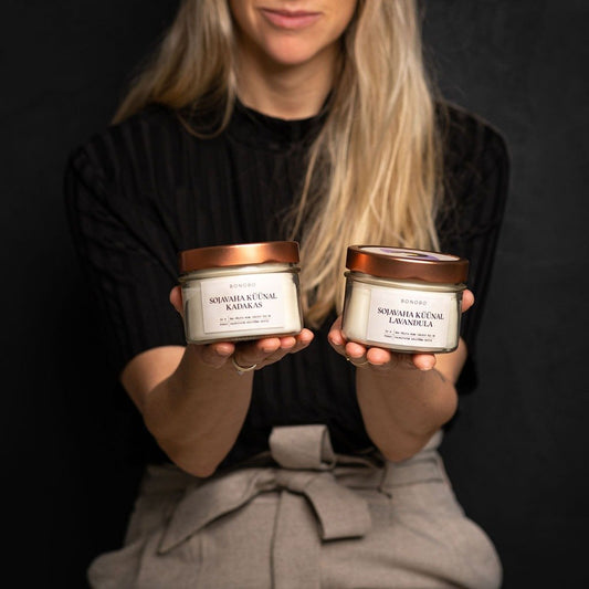 1. Woman holding two BONOBO scented candles in a lifestyle setting, featuring juniper and lavender scents