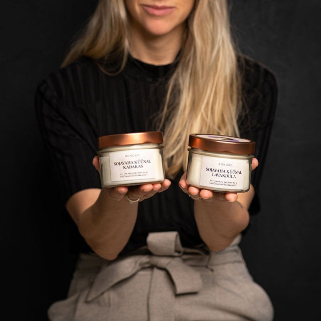 1. Woman holding two BONOBO scented candles in a lifestyle setting, featuring juniper and lavender scents