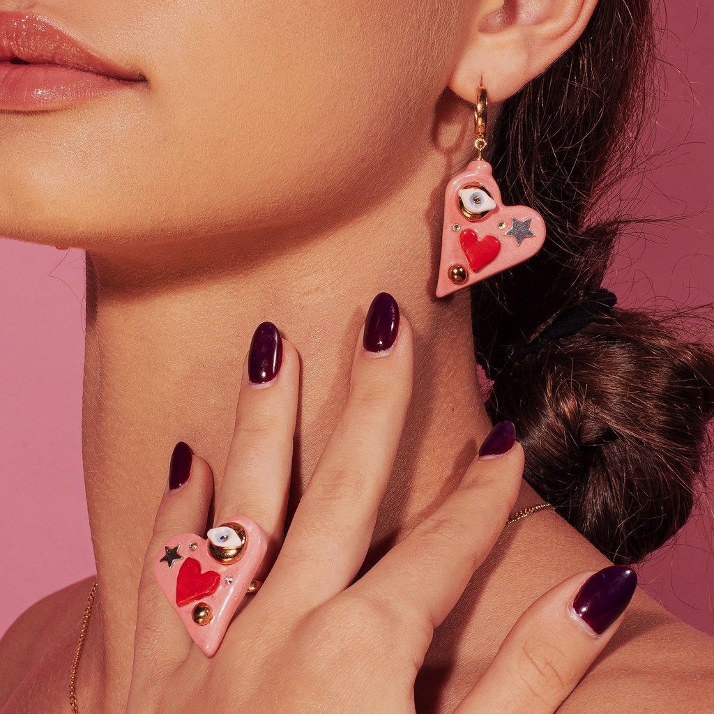 1. Woman wearing SCULP All You Need Is Love earrings with Eye of Protection charm and Swarovski crystals, shown in lifestyle setting