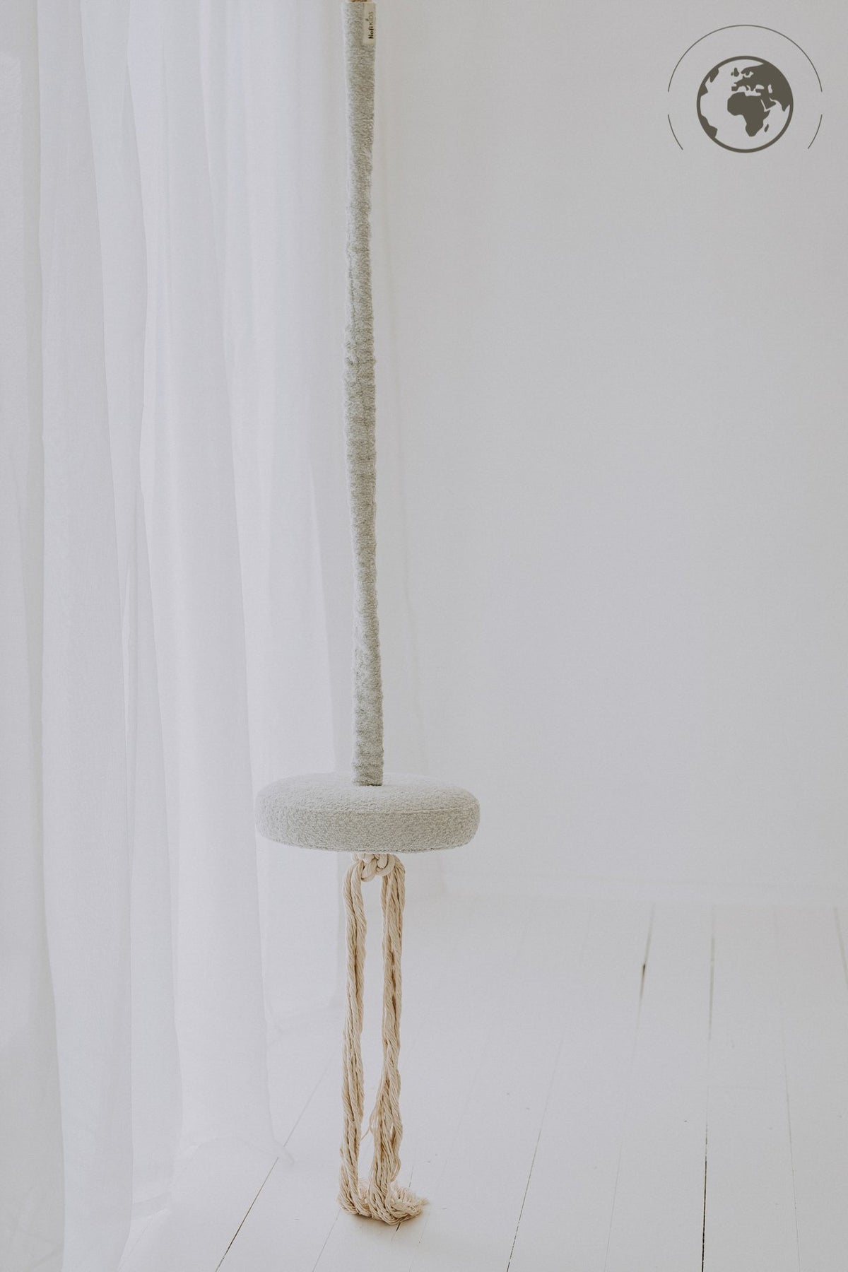 2. Ice grey bouclé swing with cotton rope hanging in a minimalistic white room