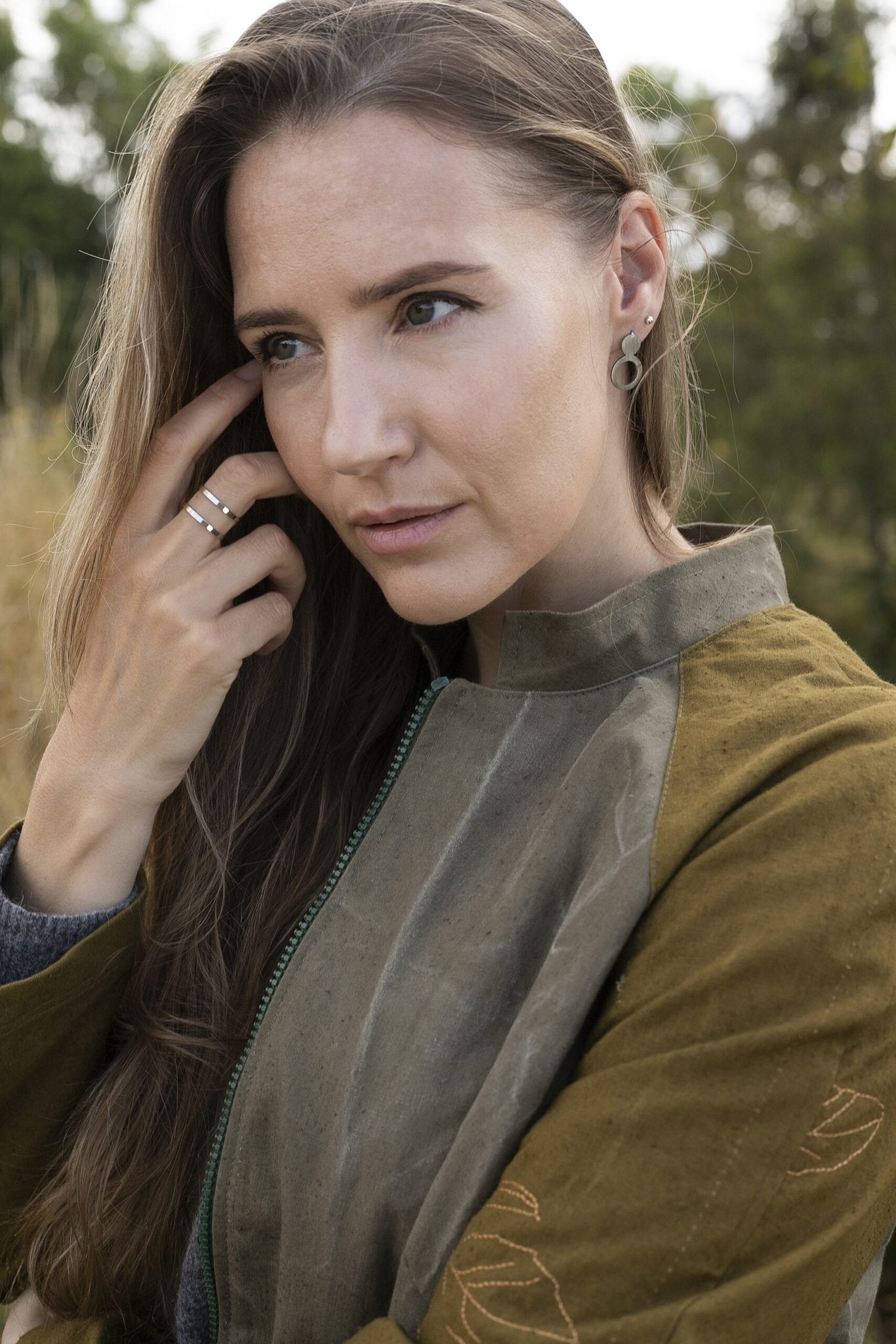 1. Woman wearing Lentsius Arc silver earrings in outdoor setting, showcasing sustainable Scandinavian design