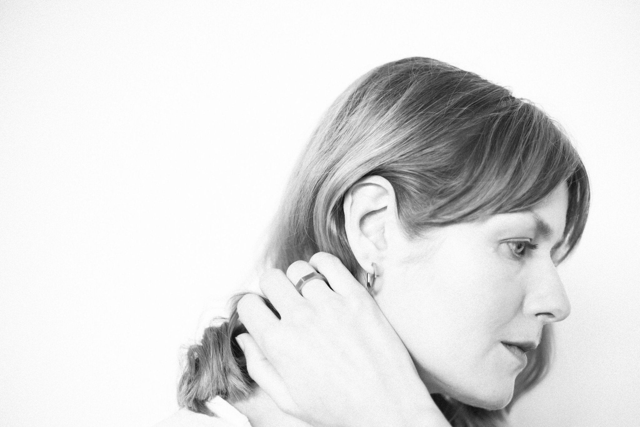 4. Close-up of woman wearing Lentsius Flecte earrings, showing polished edge and matte finish
