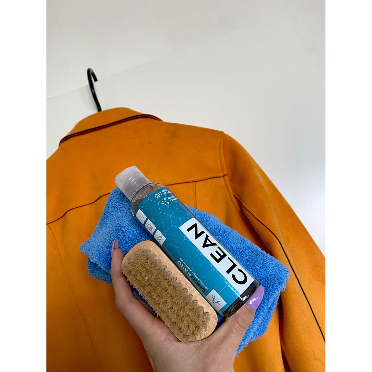 6. GoGoNano shoe cleaner gel with brush and cloth held against orange jacket