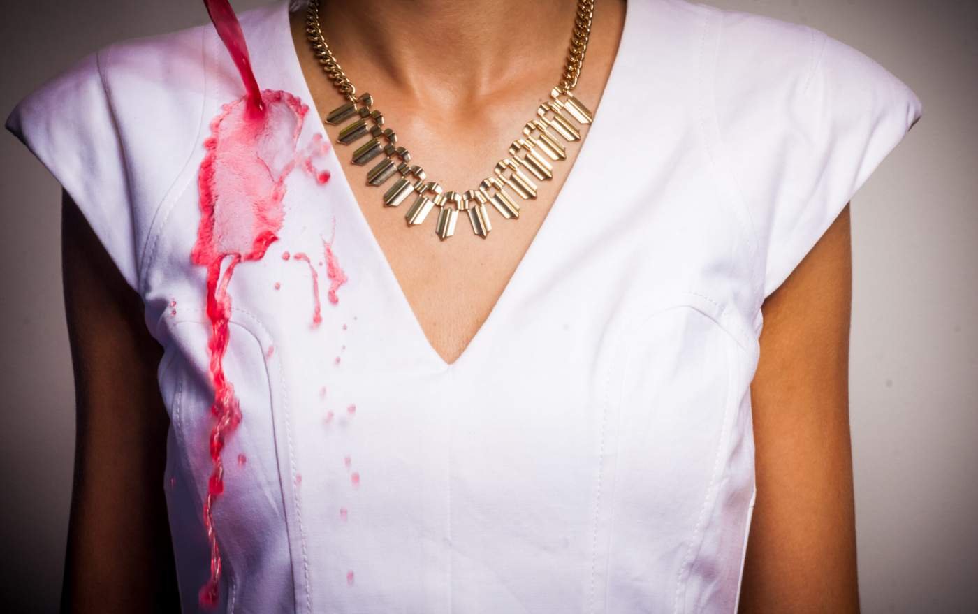 1. Woman in white dress with red liquid repelling off fabric, demonstrating GoGoNano Stay Dry Nano Coating Spray effectiveness