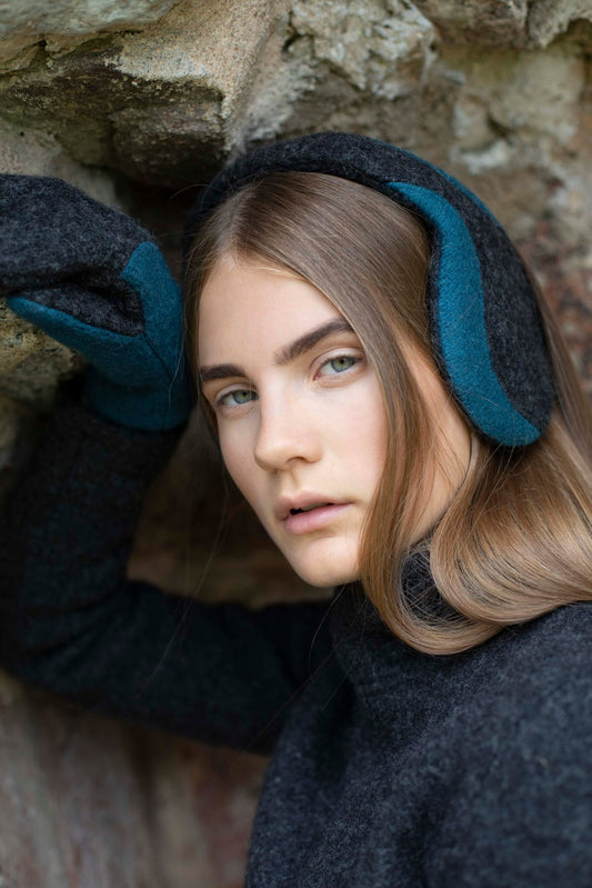 1. Woman wearing HERTTA felted wool earmuffs in dark grey and aquamarine, lifestyle setting