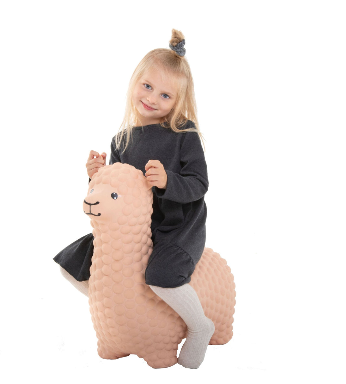 1. Young girl sitting on beige alpaca hopper toy wearing dark dress and white tights