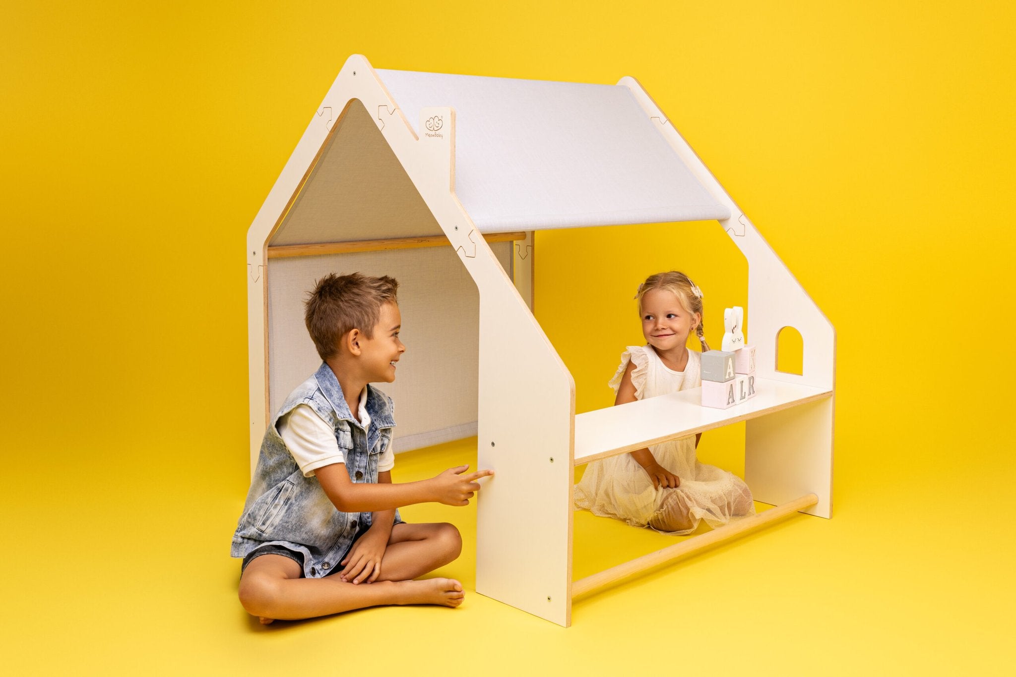1. Two children playing with white wooden playhouse on yellow background