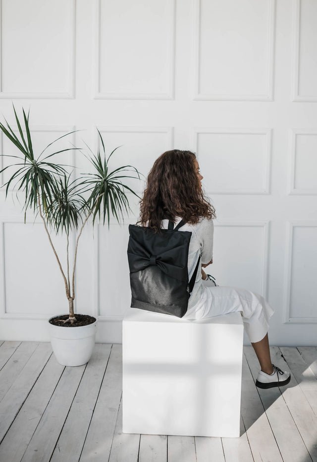 5. Woman seated with Muni Black Bow Large waterproof backpack, emphasizing comfort and style